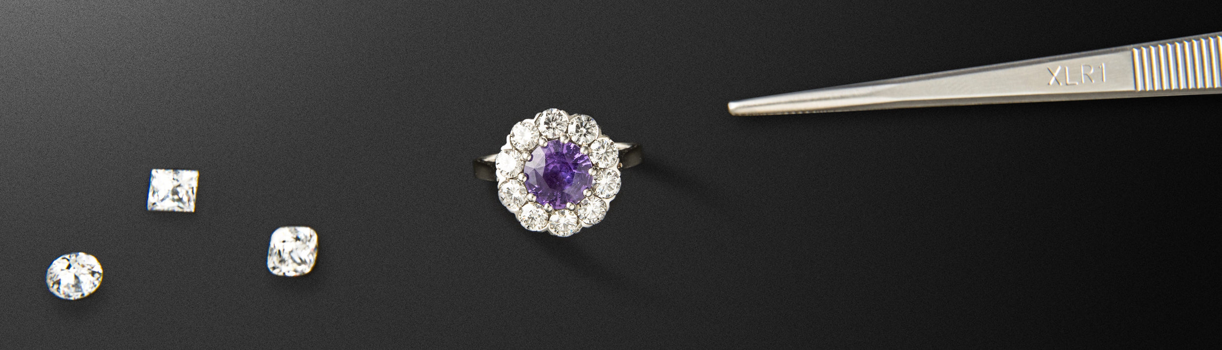 Jewelry set with a ring, two diamonds, and tweezers on a black background