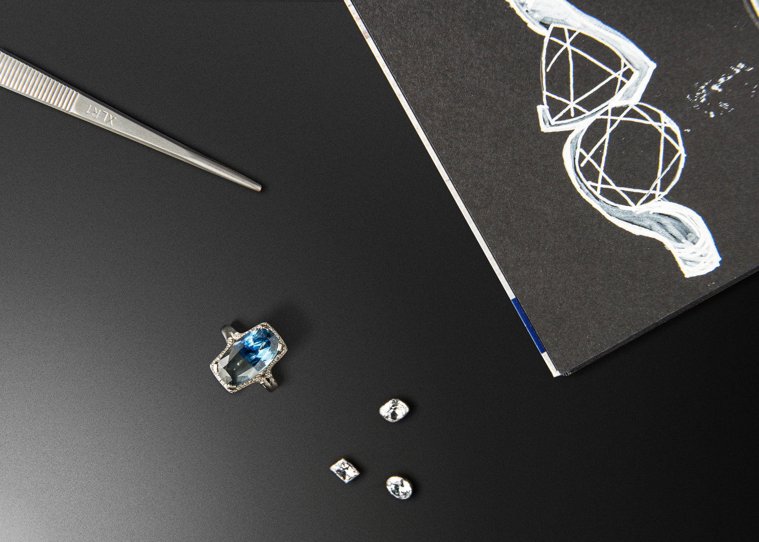 Jewelry-making tools and gemstones on a black surface with a white design.