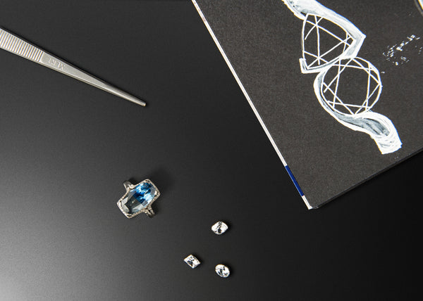 Jewelry-making tools and gemstones on a black surface with a white design.